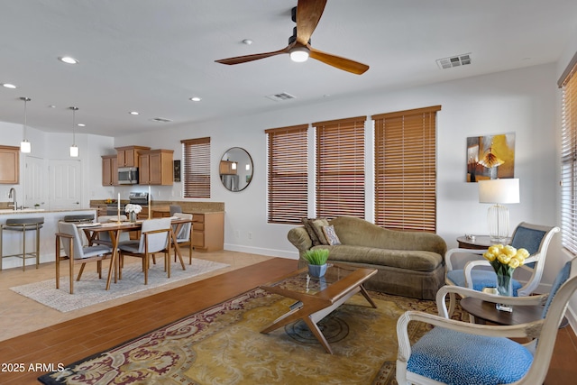 living room with light wood-style flooring, recessed lighting, baseboards, ceiling fan, and visible vents