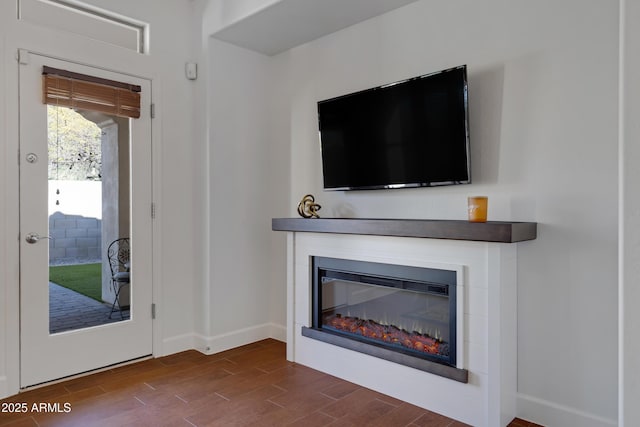 interior space featuring baseboards, dark wood finished floors, and a glass covered fireplace