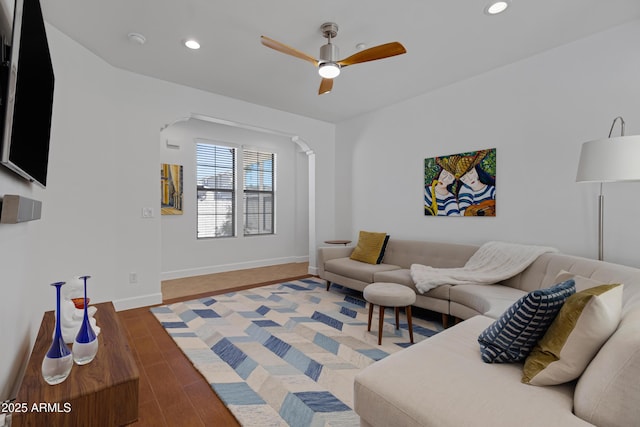 living area with wood finished floors, recessed lighting, ceiling fan, arched walkways, and baseboards