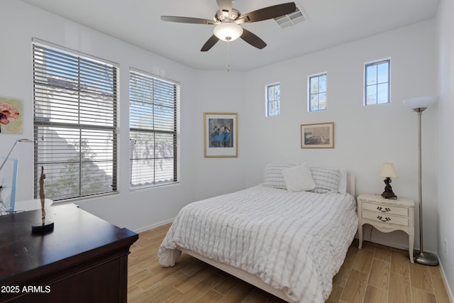 bedroom with light wood-type flooring, visible vents, baseboards, and a ceiling fan