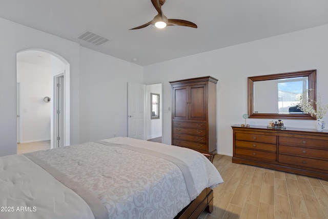 bedroom featuring visible vents, arched walkways, a ceiling fan, baseboards, and light wood-style floors