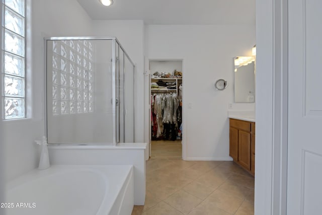 full bathroom featuring a shower stall, tile patterned floors, vanity, a garden tub, and a spacious closet