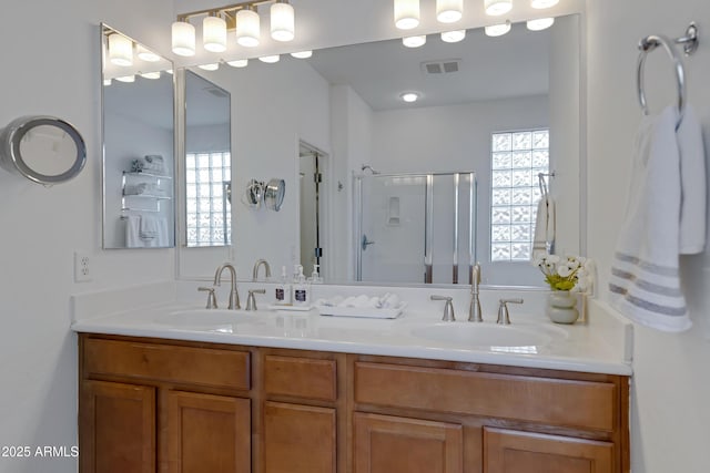bathroom featuring a stall shower, visible vents, a sink, and double vanity