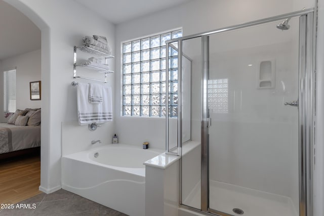 ensuite bathroom featuring a stall shower and a bath