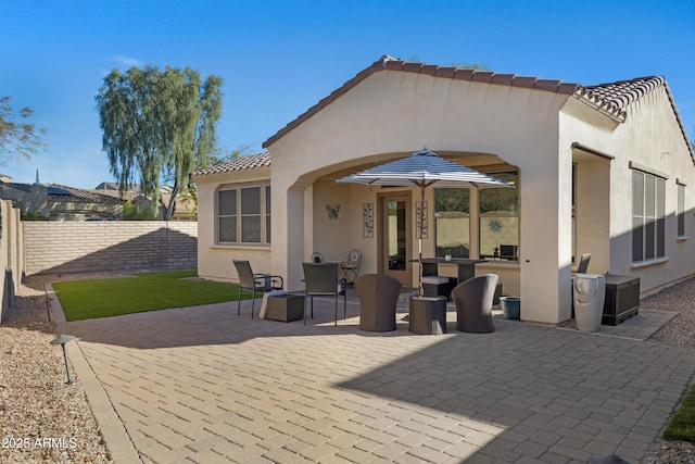 back of house with a fenced backyard, stucco siding, a patio area, and a tile roof