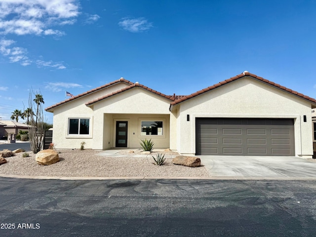 mediterranean / spanish house with stucco siding, driveway, an attached garage, and a tile roof