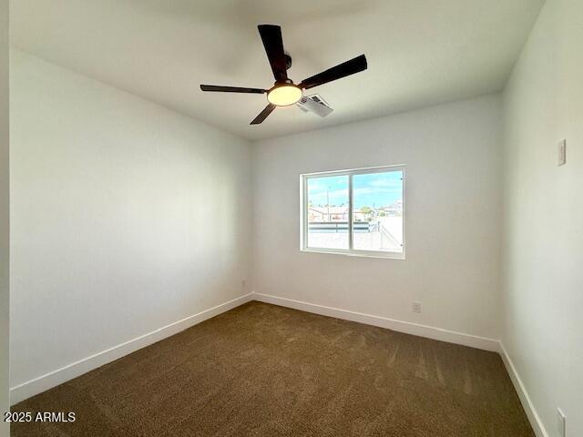 unfurnished room featuring dark carpet, baseboards, and ceiling fan