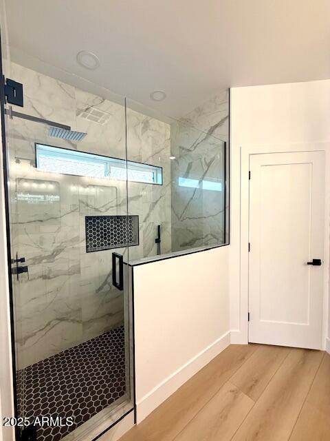 bathroom featuring a marble finish shower and wood finished floors