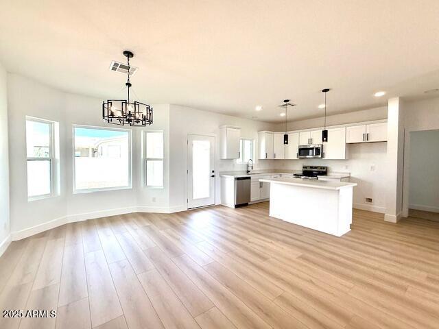 kitchen featuring visible vents, light wood-style flooring, stainless steel appliances, light countertops, and a center island