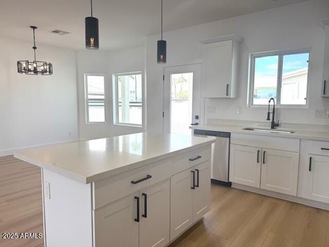 kitchen with stainless steel dishwasher, light countertops, light wood-style floors, and a sink