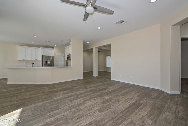 unfurnished living room featuring ceiling fan, dark hardwood / wood-style flooring, and sink