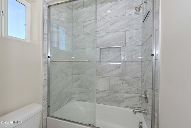 bathroom featuring enclosed tub / shower combo and toilet