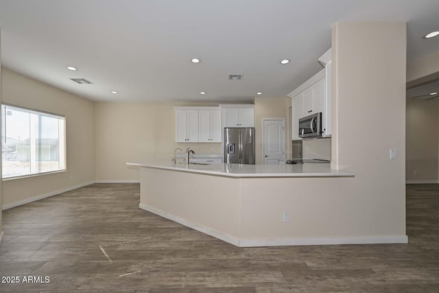 kitchen featuring dark wood-type flooring, sink, stainless steel appliances, and white cabinetry