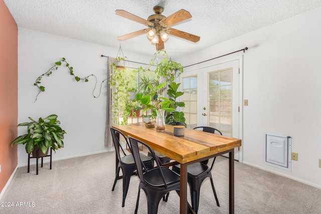 dining space featuring french doors, ceiling fan, light carpet, and a textured ceiling