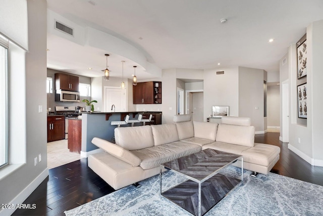 living room featuring wood finished floors, visible vents, and baseboards