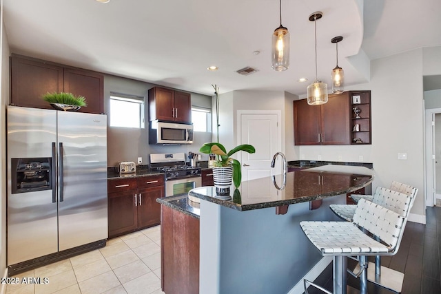 kitchen with visible vents, a breakfast bar, light tile patterned floors, hanging light fixtures, and stainless steel appliances