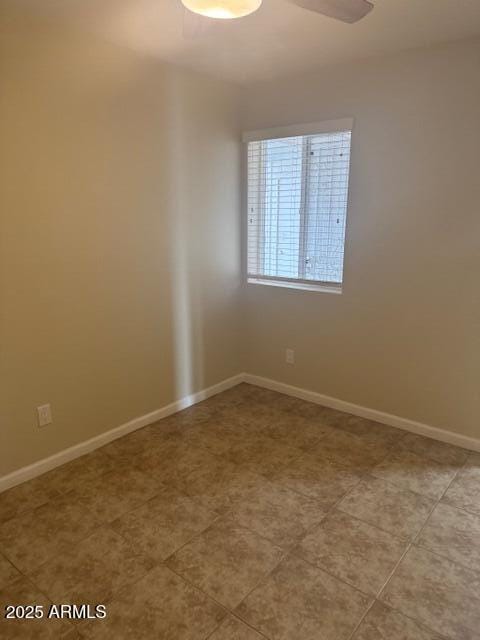 tiled spare room featuring ceiling fan