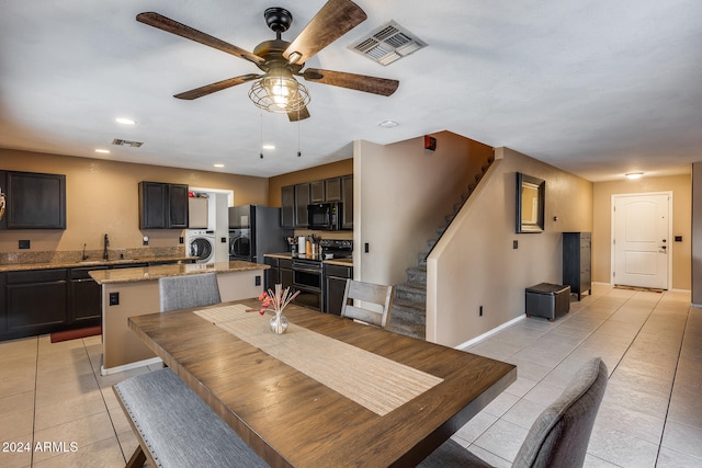 tiled dining space featuring sink, ceiling fan, and washer / dryer