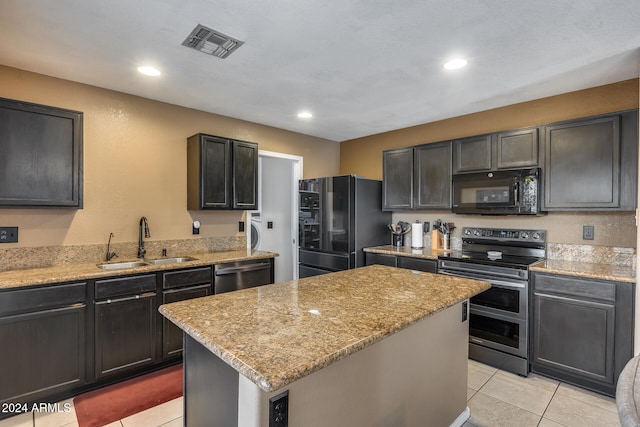 kitchen featuring black appliances, light tile patterned floors, light stone countertops, sink, and a center island