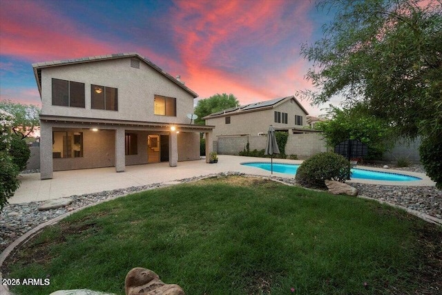 back house at dusk with a yard, a fenced in pool, and a patio area