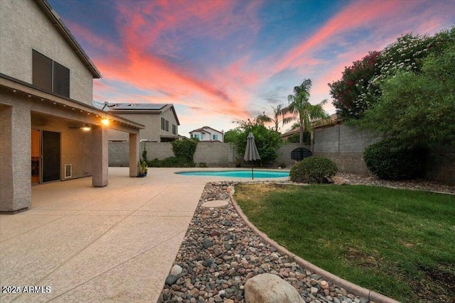 pool at dusk featuring a yard and a patio area