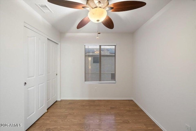 unfurnished bedroom featuring hardwood / wood-style floors, a closet, and ceiling fan