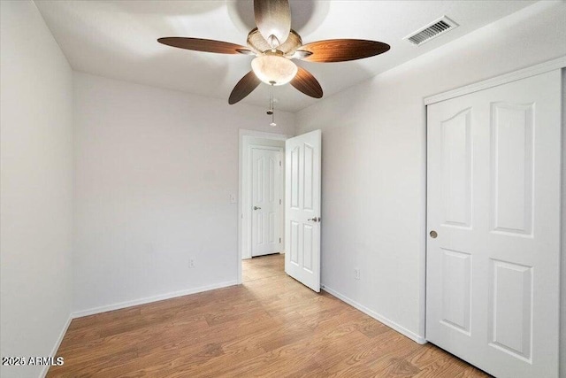 unfurnished bedroom with ceiling fan, light wood-type flooring, and a closet