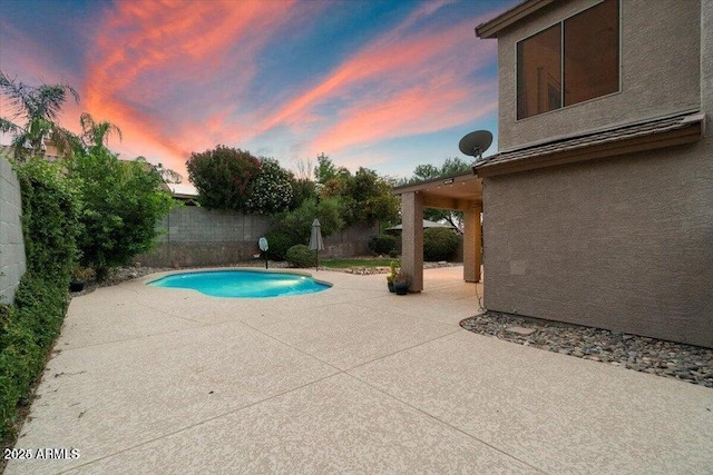 pool at dusk featuring a patio