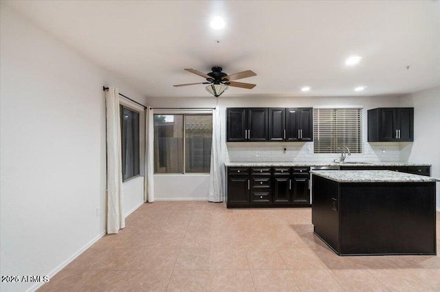 kitchen featuring a center island, sink, backsplash, and ceiling fan