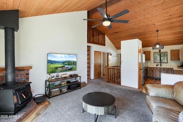 living area with wood ceiling, a wood stove, light carpet, and ceiling fan