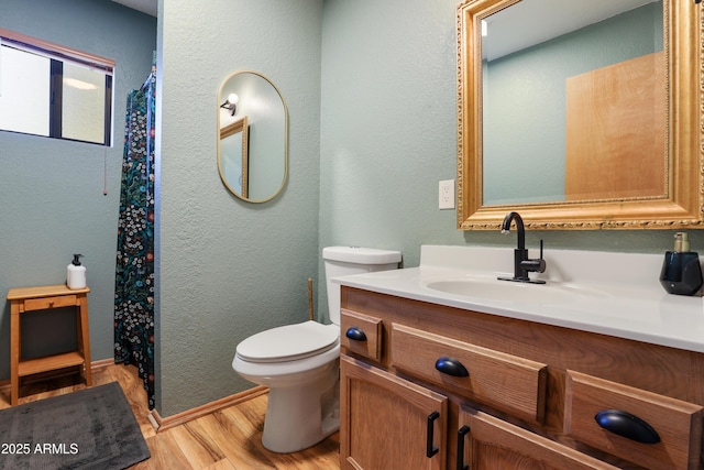 bathroom featuring a textured wall, vanity, toilet, and wood finished floors