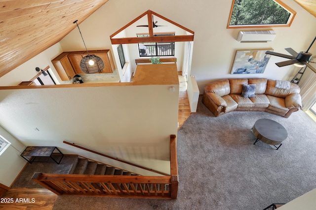 living area with a wall mounted air conditioner, vaulted ceiling, a ceiling fan, and wood finished floors