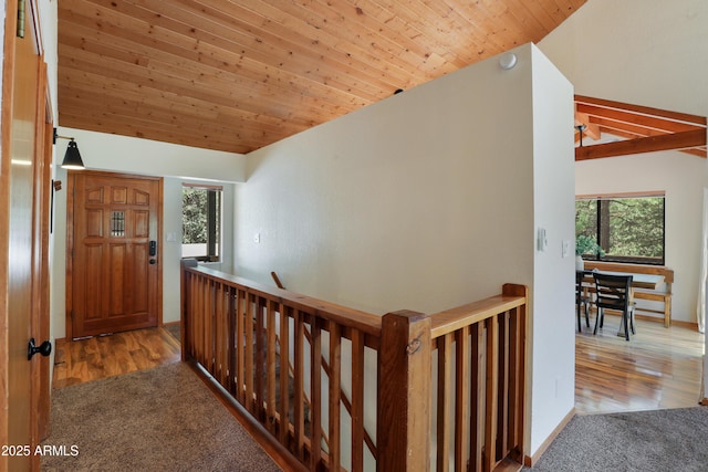 hall featuring lofted ceiling, wooden ceiling, wood finished floors, carpet, and an upstairs landing