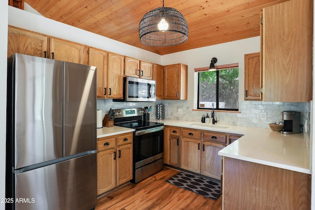 kitchen with stainless steel appliances, a sink, light countertops, and pendant lighting