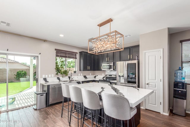 4135 E Waterman Ct, Gilbert, AZ 85297 - kitchen featuring stainless steel appliances, dark wood-style flooring, a kitchen island, a kitchen bar, and light stone countertops