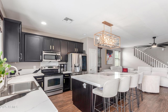 4135 E Waterman Ct, Gilbert, AZ 85297 - kitchen with appliances with stainless steel finishes, open floor plan, a sink, dark wood finished floors, and hanging light fixtures