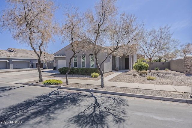 view of front of house featuring a garage, fence, concrete driveway, and stucco siding