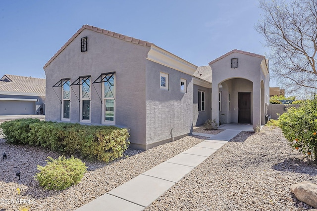 mediterranean / spanish home featuring a tile roof and stucco siding