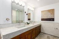 bathroom with double vanity, tile walls, and a wainscoted wall