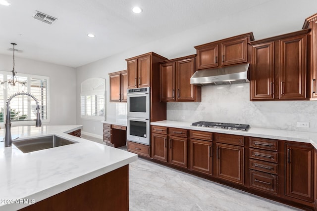 kitchen featuring pendant lighting, sink, decorative backsplash, appliances with stainless steel finishes, and a chandelier