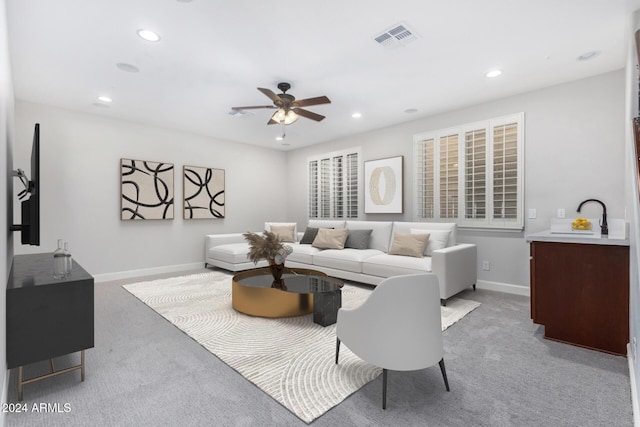 living room with ceiling fan, sink, and light carpet