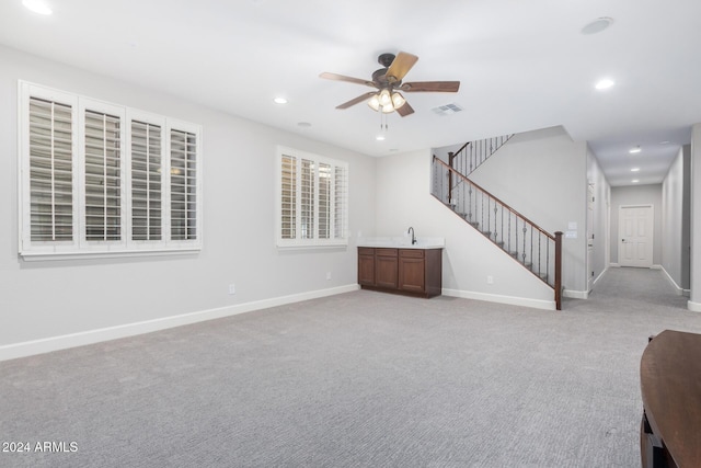 unfurnished living room with light colored carpet and ceiling fan