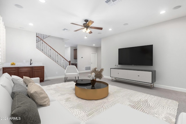 living room featuring light carpet, sink, and ceiling fan