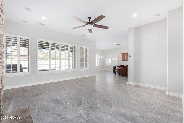 unfurnished living room with ceiling fan with notable chandelier