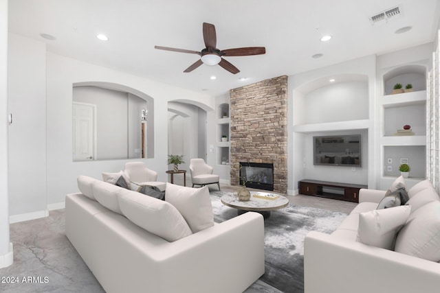 living room with a fireplace, built in features, and ceiling fan