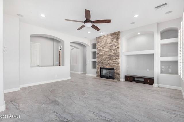 unfurnished living room featuring a fireplace, ceiling fan, and built in features