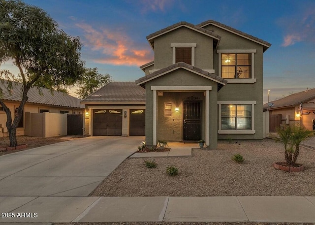 traditional-style home featuring stucco siding, driveway, a tile roof, fence, and an attached garage