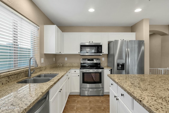 kitchen with a sink, white cabinetry, appliances with stainless steel finishes, and light tile patterned floors