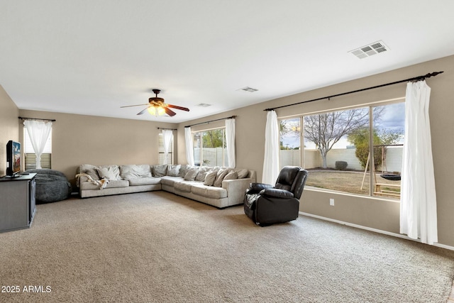 carpeted living area featuring a wealth of natural light, visible vents, and a ceiling fan