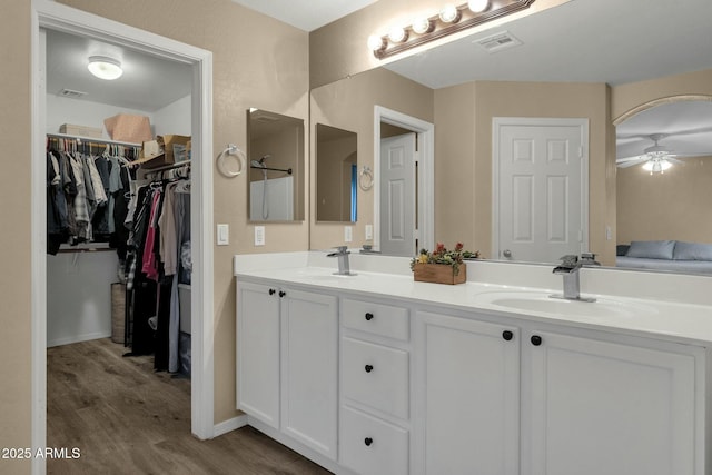 bathroom with double vanity, wood finished floors, visible vents, and a sink